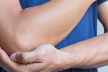 Photograph of person holding elbow because of pain